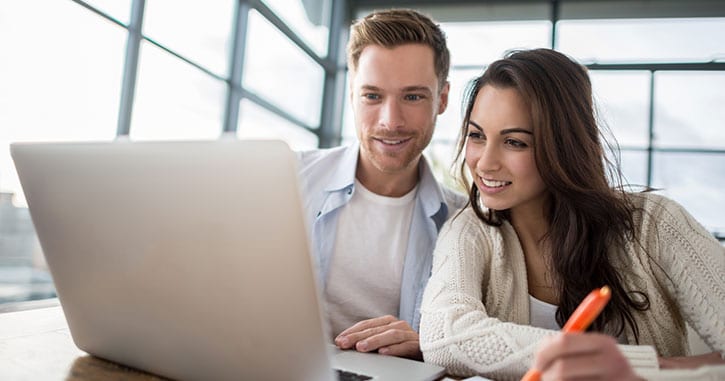 Couple smiling while checking their credit score - does checking your credit score lower it?