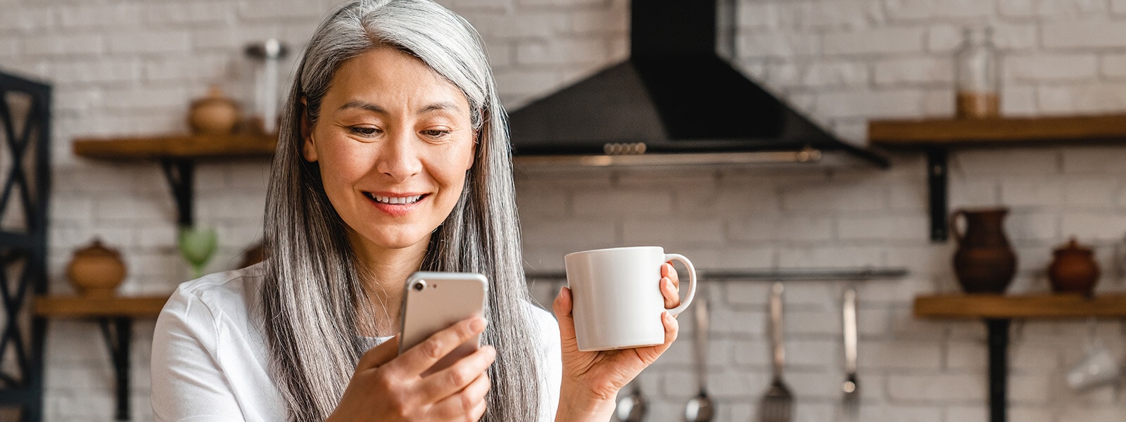 Woman with a coffee mug looking at her phone to look up what a good credit score is.