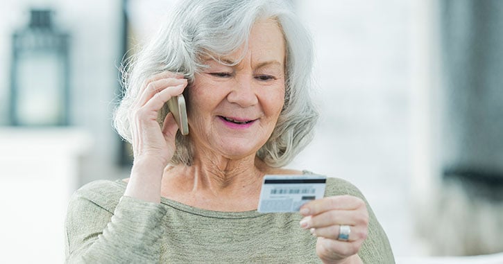 Woman on phone looking at credit card