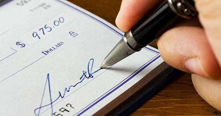 A person confidently signing a check for a secure financial transaction, illustrating the importance of identity protection from check fraud.