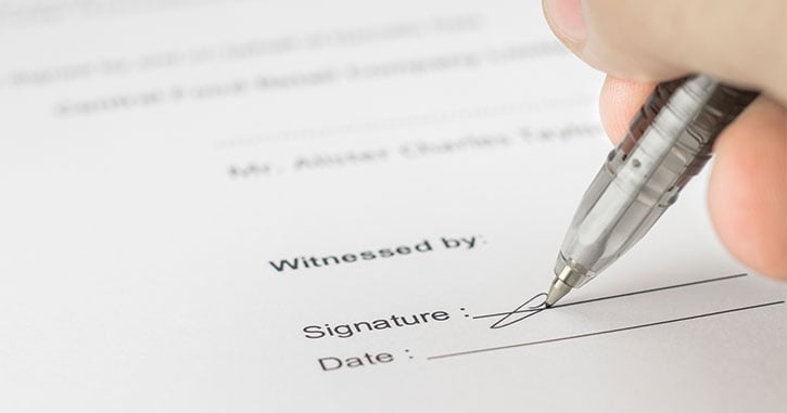 A notary public witnessing a signature on a deed, illustrating the potential for deed fraud and the risk of losing one's home with the stroke of a pen.