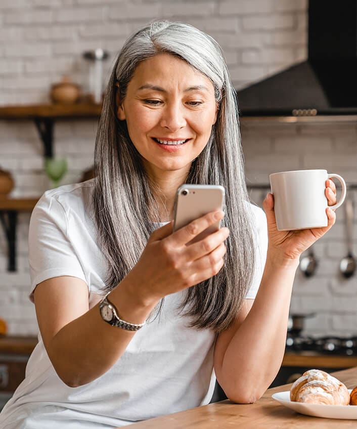 Woman with a coffee mug looking at her phone to look up what a good credit score is.