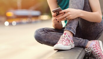 Young person sitting holding smart phone