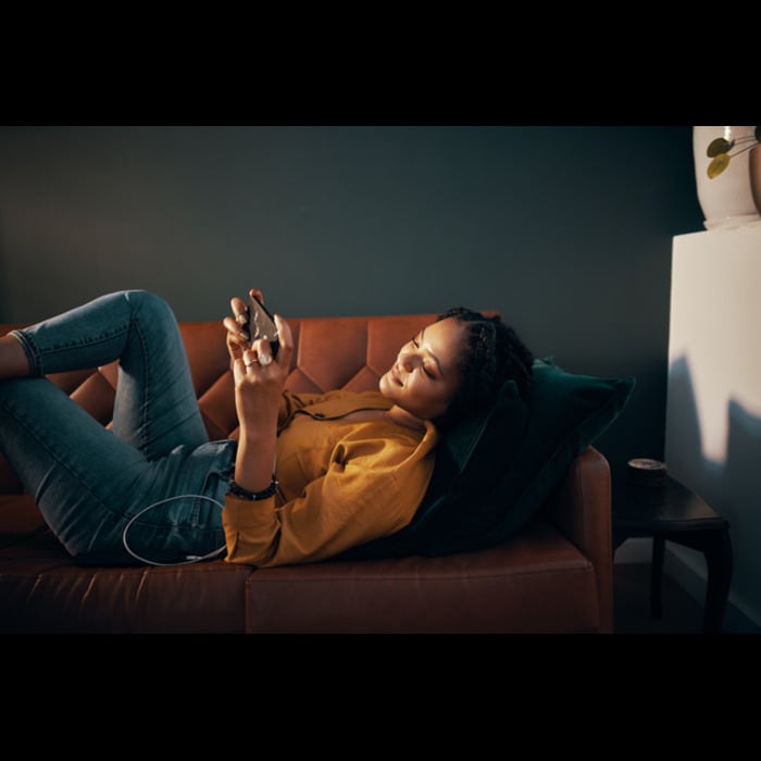 A woman laying on the couch holding a device.